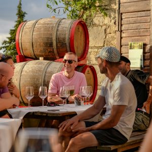 Visiteurs participant à une expérience œnotouristique devant des barriques